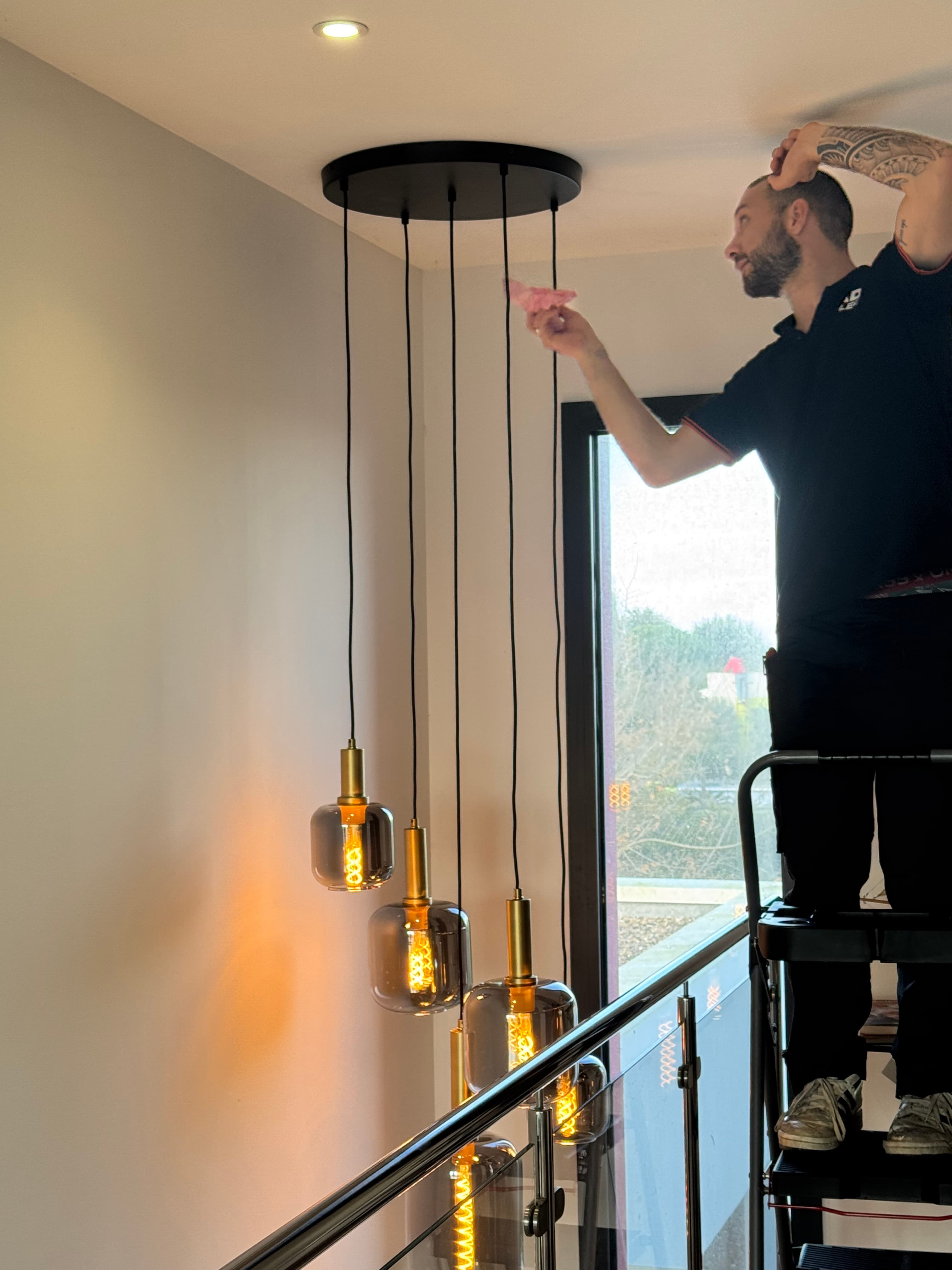Électricien près de suspensions lumineuses dans un intérieur