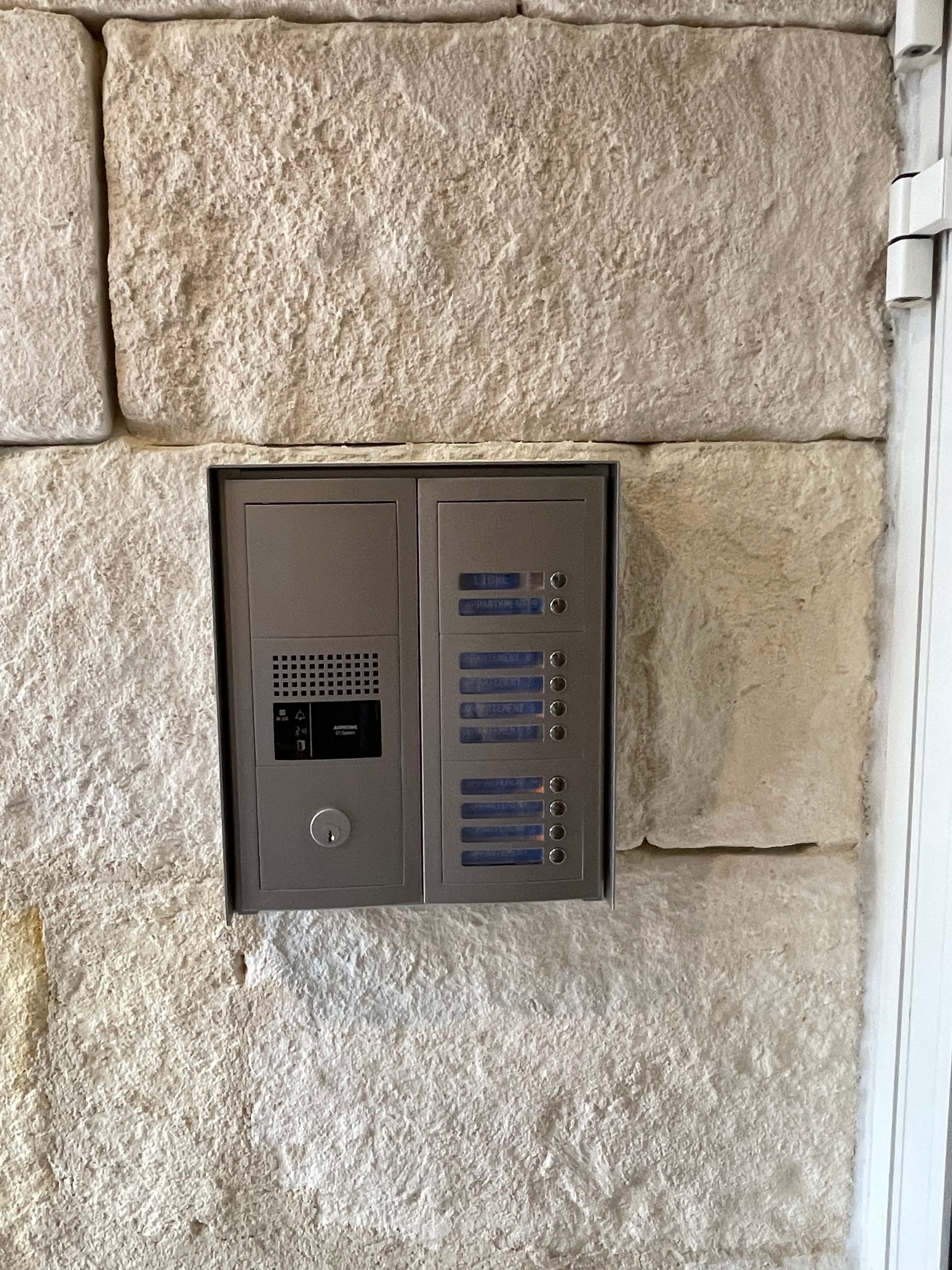 Platine d’interphone collective encastrée dans une façade en pierre