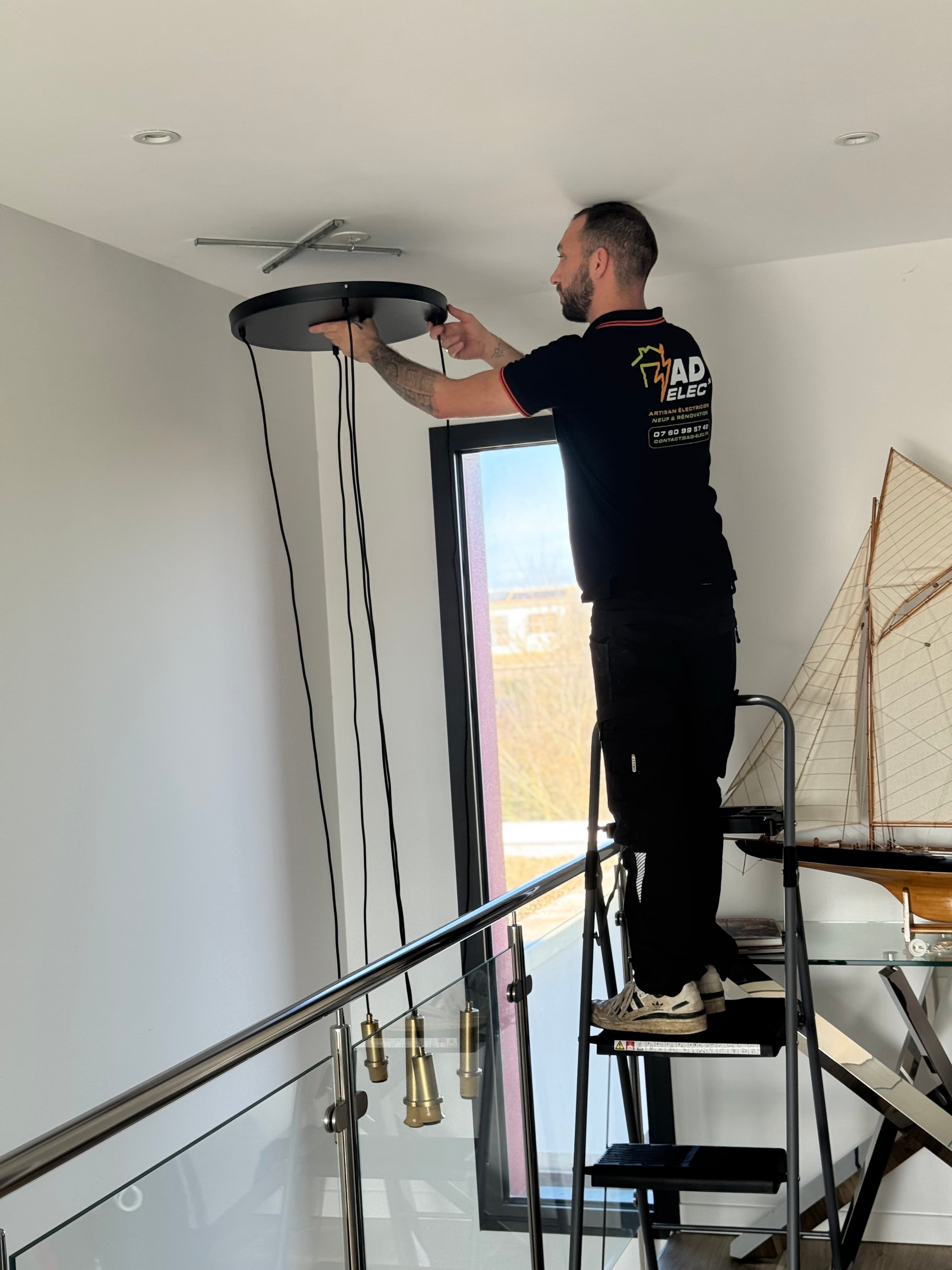 Électricien installant un luminaire suspendu dans un escalier